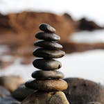 A stack of smooth stones artfully balanced by a waterside, evoking tranquility and zen.